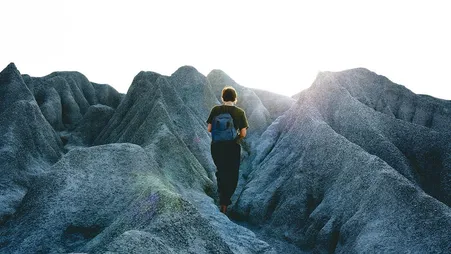 Person wandert allein durch eine graue Felslandschaft
